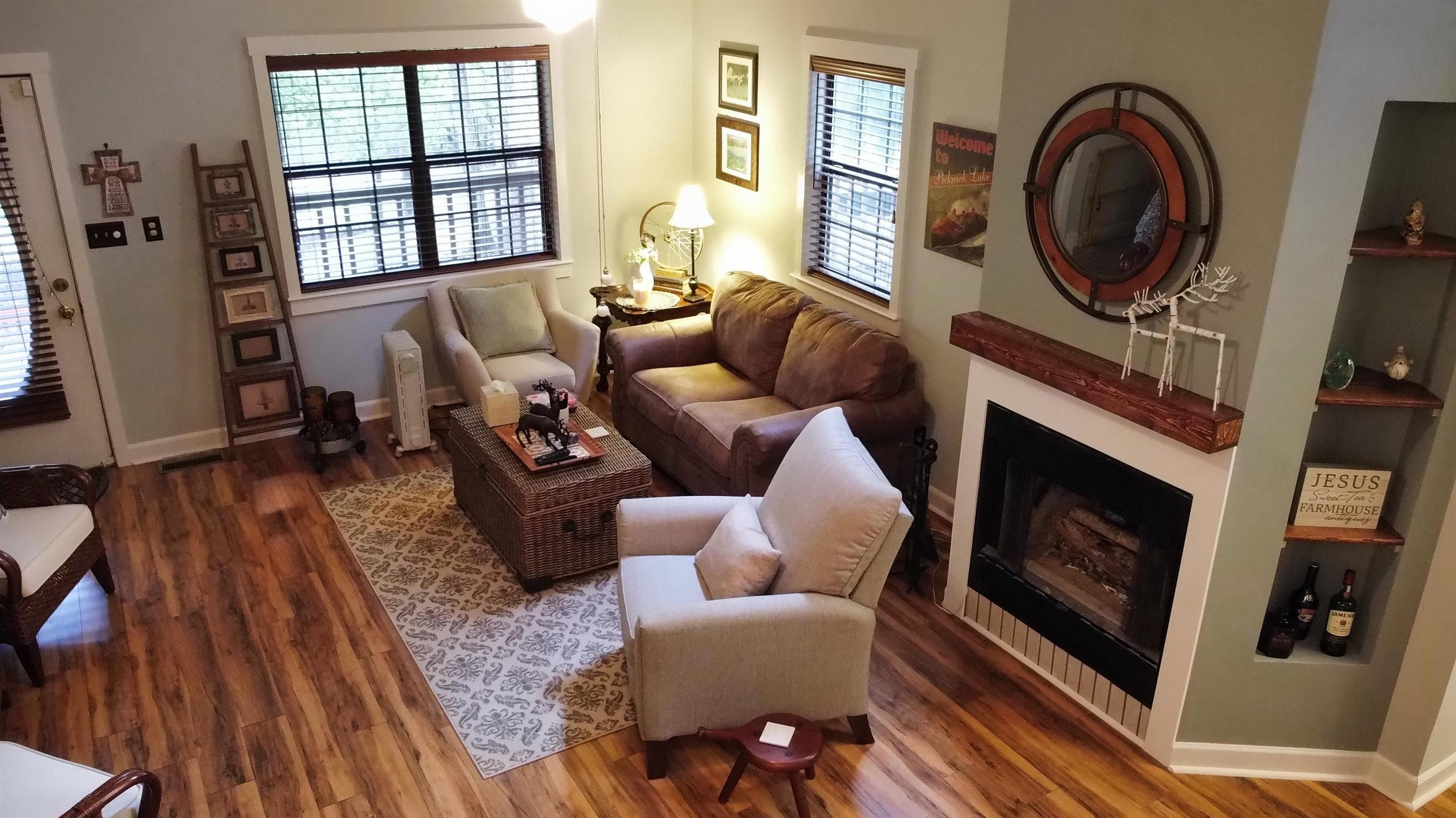 275 Bryson Harbor Road Counce, TN 38326 - Photo 14 of 23 Living area featuring wood-finish flooring, a fireplace with a wood mantel, built-in corner shelving, and multiple windows with blinds