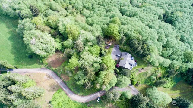 an aerial view of residential house with outdoor space and trees all around