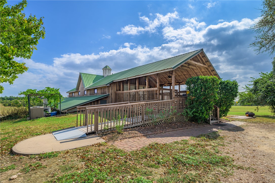 1441 Salem Road Brenham, TX 77833 - Photo 11 of 34 Back of property featuring a metal roof, a deck, a patio area, and a lawn