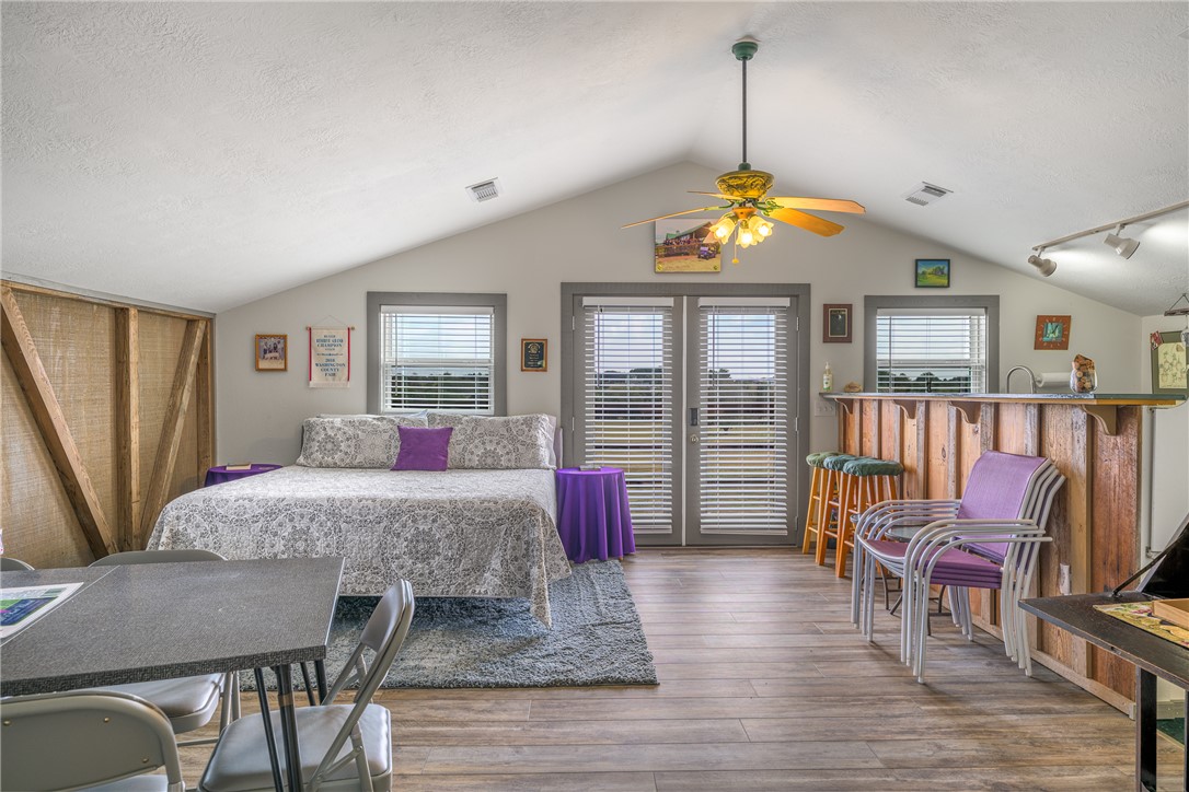 1441 Salem Road Brenham, TX 77833 - Photo 22 of 34 Bedroom with multiple windows, lofted ceiling, wood finished floors, a textured ceiling, and ceiling fan