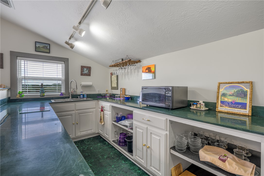 1441 Salem Road Brenham, TX 77833 - Photo 23 of 34 Kitchen featuring track lighting, white cabinetry, vaulted ceiling, a textured ceiling, and black microwave