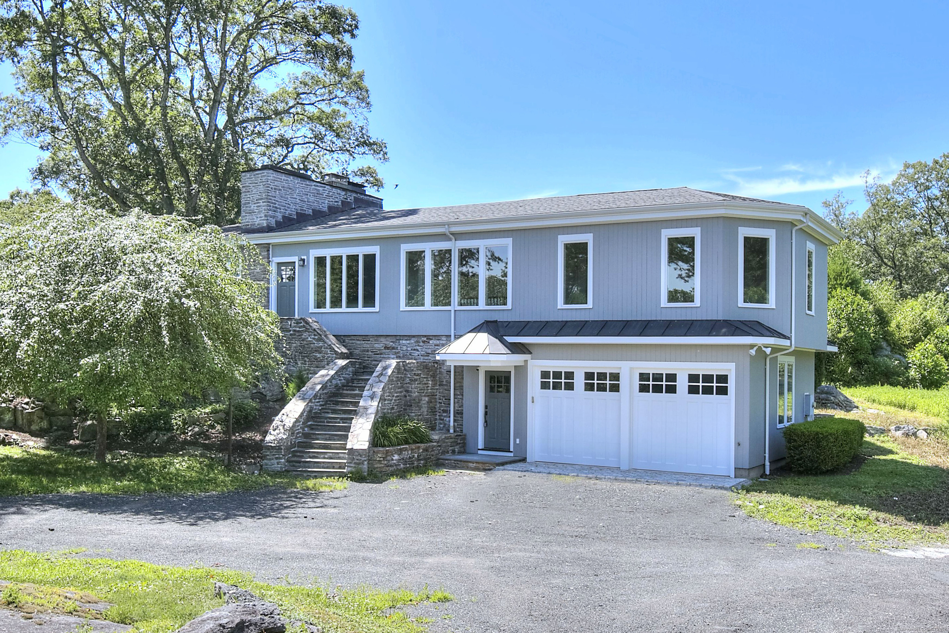 27 Rogues Ridge Road Weston, CT 06883 - Photo 2 of 39 a front view of a house with a yard and garage