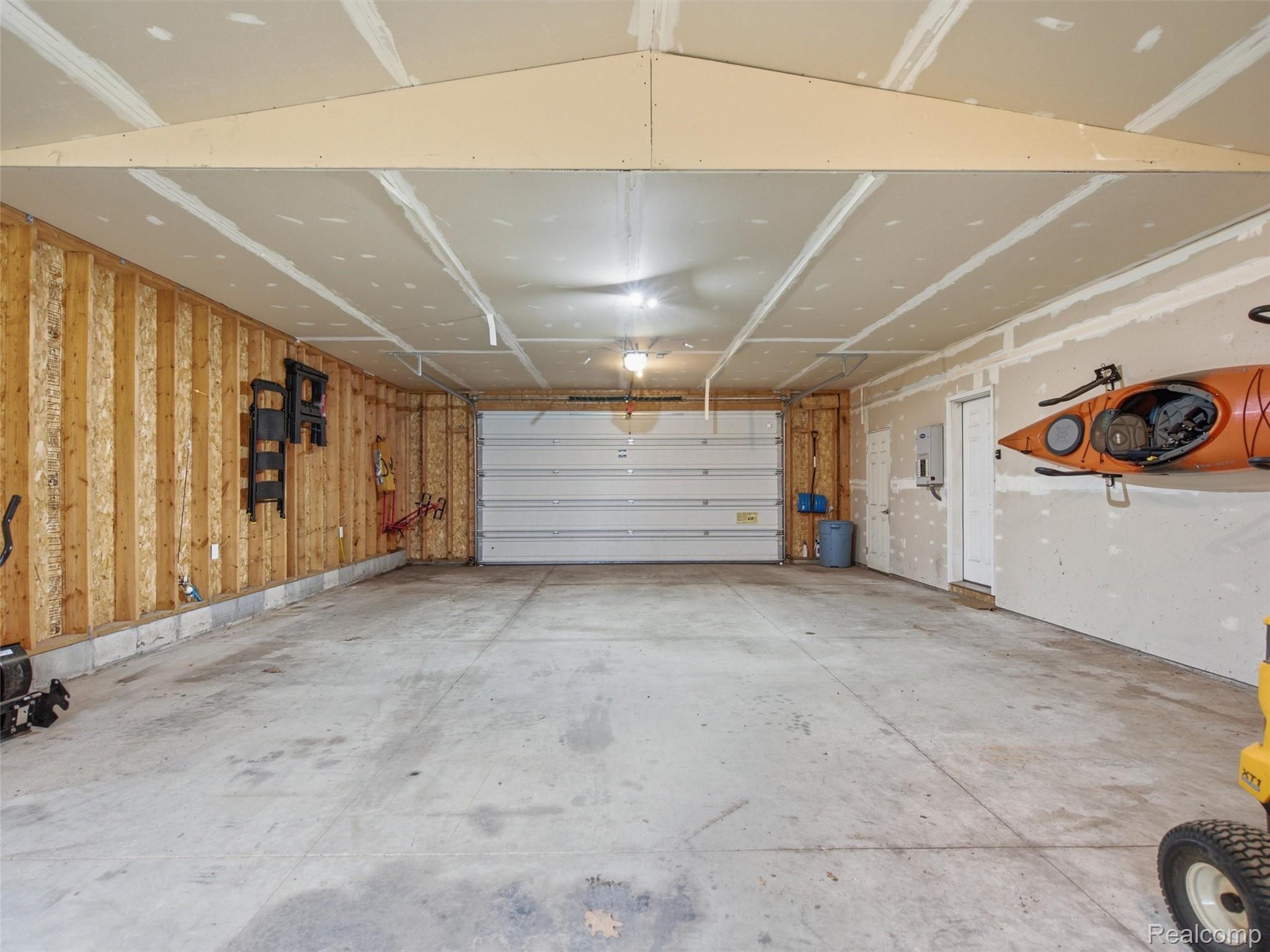 5003 Mason Road Howell, MI 48843 - Photo 46 of 59 Spacious garage featuring a concrete floor, exposed wooden wall studs, drywall ceiling, and an overhead garage door