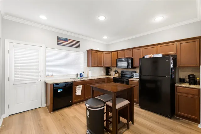 a kitchen with stainless steel appliances a refrigerator a sink a stove a dining table and chairs