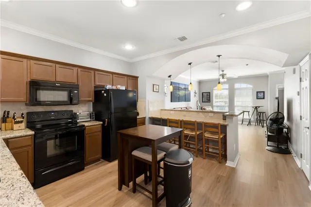 a kitchen with stainless steel appliances granite countertop a refrigerator a stove top oven a sink dishwasher and white cabinets with wooden floor