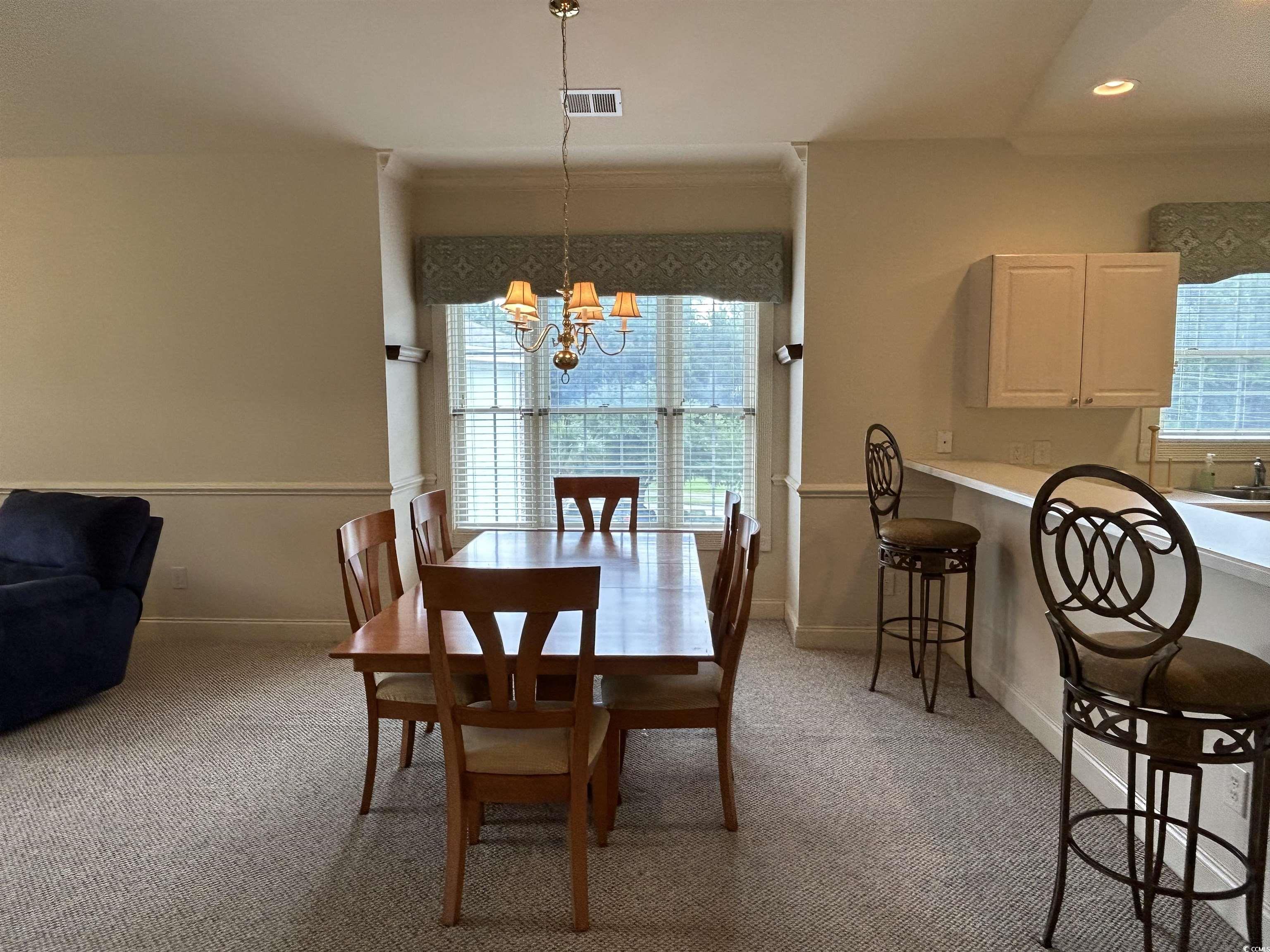 4893 Magnolia Pointe Lane, Unit 305 Myrtle Beach, SC 29577 - Photo 13 of 36 Dining area featuring a chandelier, light carpet, and ornamental molding