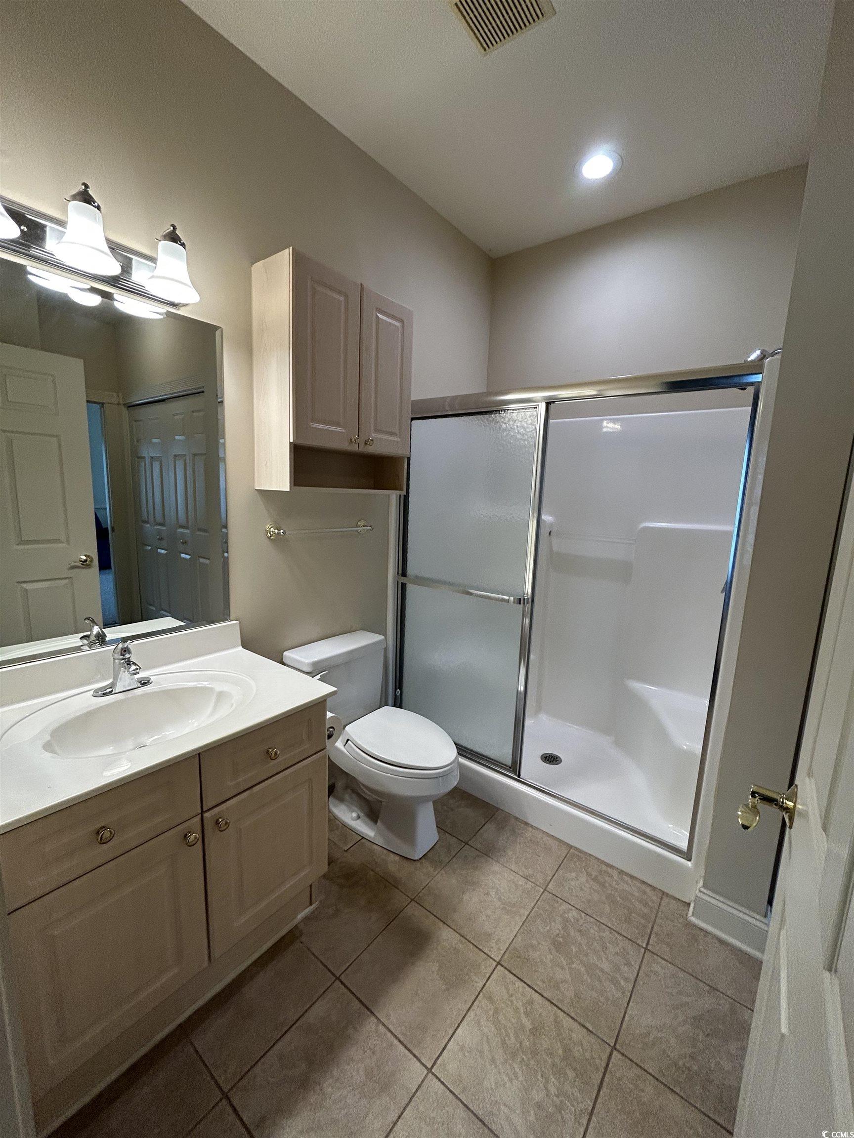 4893 Magnolia Pointe Lane, Unit 305 Myrtle Beach, SC 29577 - Photo 17 of 36 Bathroom featuring tile patterned flooring, vanity, toilet, and a shower with shower door