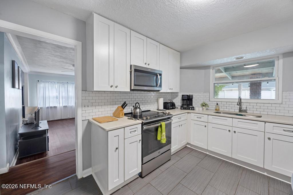 892 Trinidad Road Jacksonville, FL 32216 - Photo 9 of 37 a kitchen with stainless steel appliances granite countertop a stove top oven a sink dishwasher and a refrigerator with wooden cabinets
