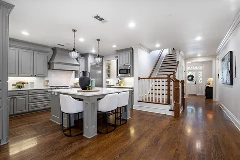 a kitchen with stainless steel appliances kitchen island granite countertop a stove a sink a dining table and chairs with wooden floor