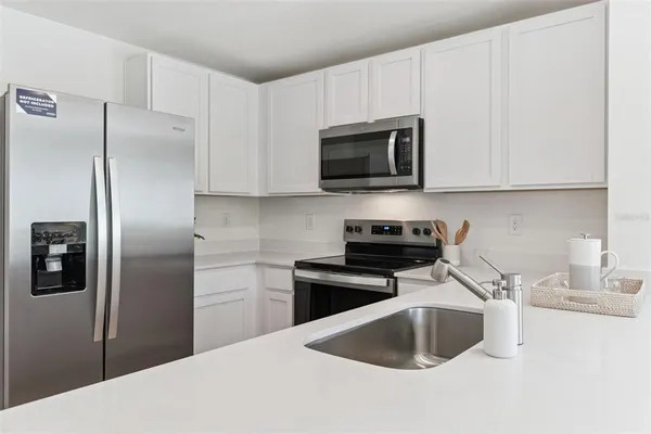 a kitchen with stainless steel appliances a refrigerator a sink a stove a microwave and cabinets