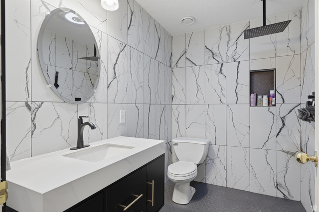 114 North Clark Lane Elk Ridge, UT 84651 - Photo 20 of 26 Contemporary bathroom featuring large format marble-look wall tiling, a rectangular vessel sink with a matte black faucet, and a wall-mounted matte black rainfall showerhead