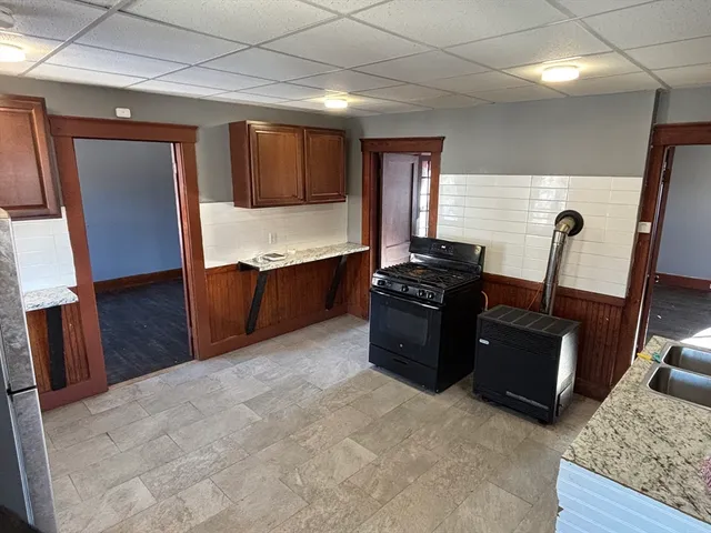 a kitchen with black cabinets and wooden floor