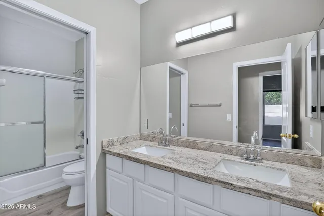a bathroom with a granite countertop sink a toilet and a large mirror