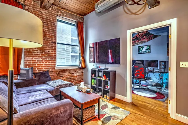 a living room with furniture and a dining table with wooden floor