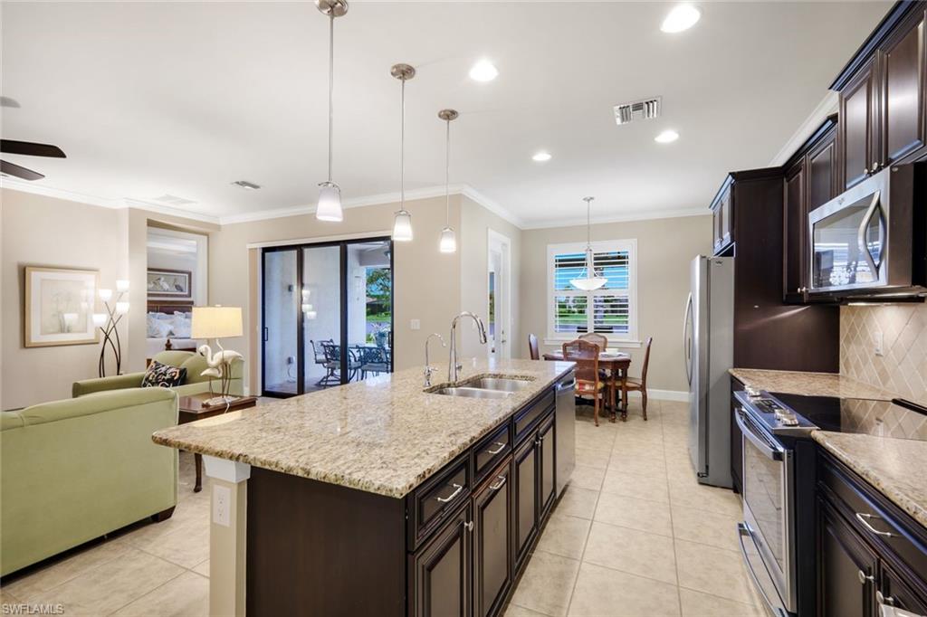 10820 Rutherford Road Fort Myers, FL 33913 - Photo 12 of 42 Kitchen island with granite countertop, stainless steel appliances, dark wood-finish cabinetry, and tile flooring