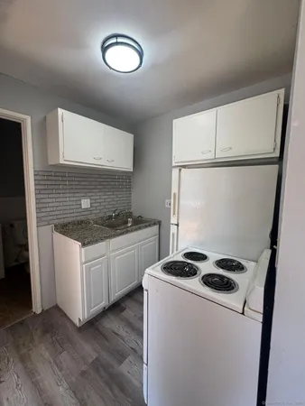 a kitchen with granite countertop a sink a stove and refrigerator
