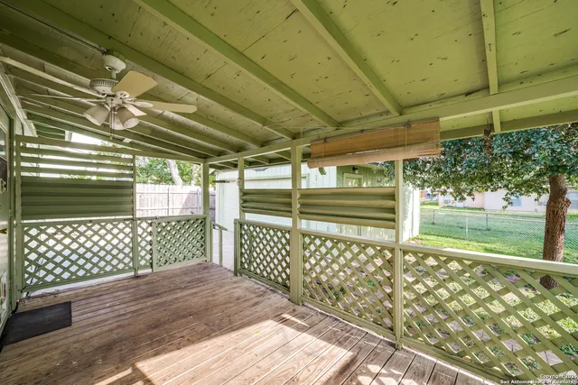 a view of a backyard with large trees and wooden fence