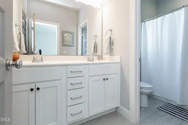 a bathroom with a double vanity sink toilet and a mirror