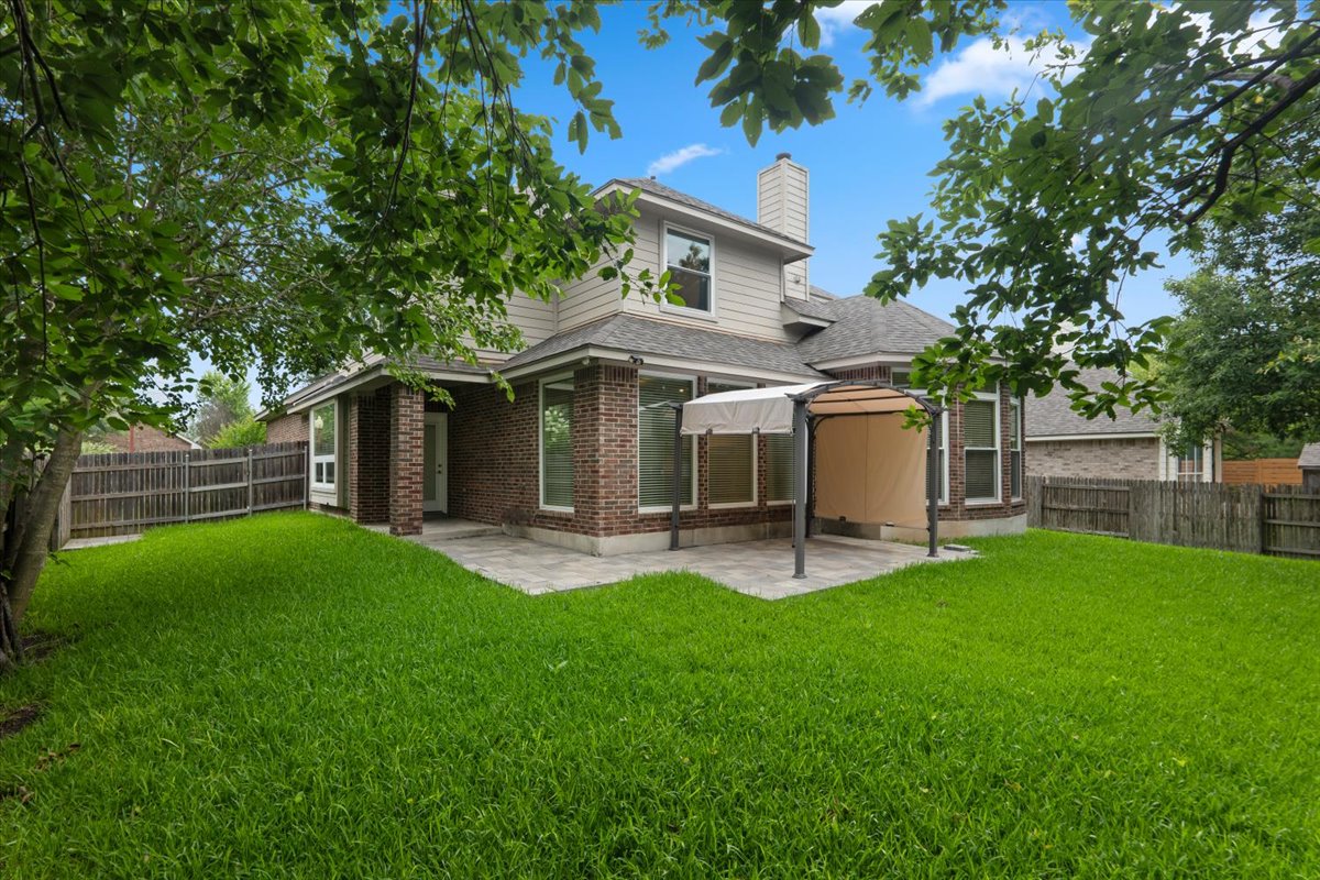 2304 Village View Loop Pflugerville, TX 78660 - Photo 4 of 40 A well-maintained yard offers a spacious lawn and an inviting paved patio perfect for outdoor enjoyment.