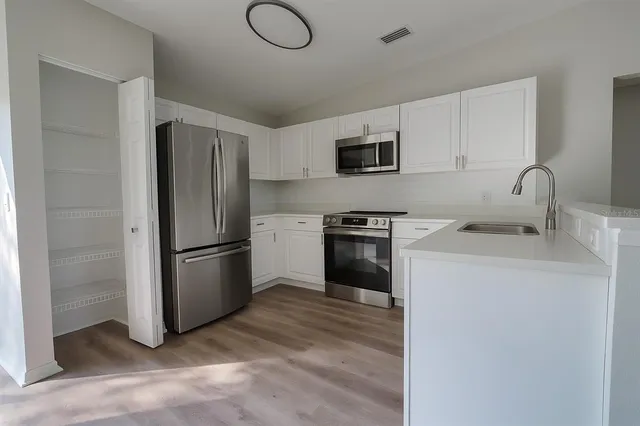 a kitchen with a refrigerator sink and white cabinets