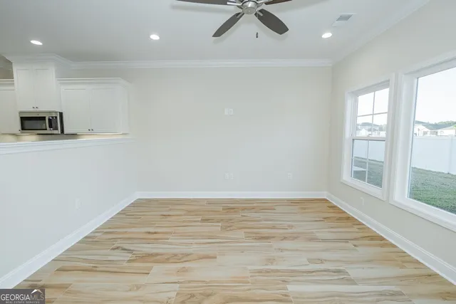 a view of empty room with wooden floor and fan