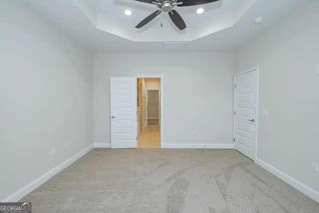 an empty room with a ceiling fan and carpet