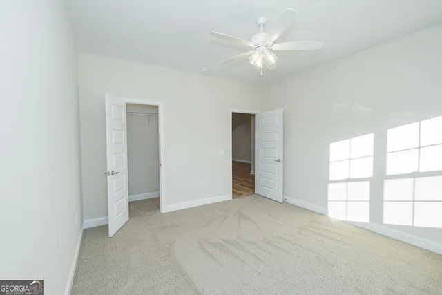 an empty room with windows and ceiling fan