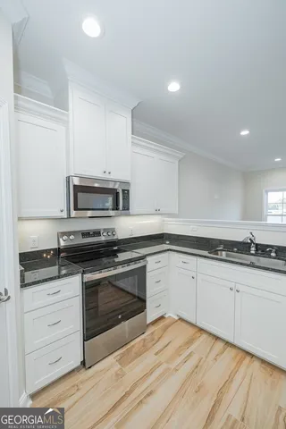 a kitchen with stainless steel appliances granite countertop a stove a sink and white cabinets