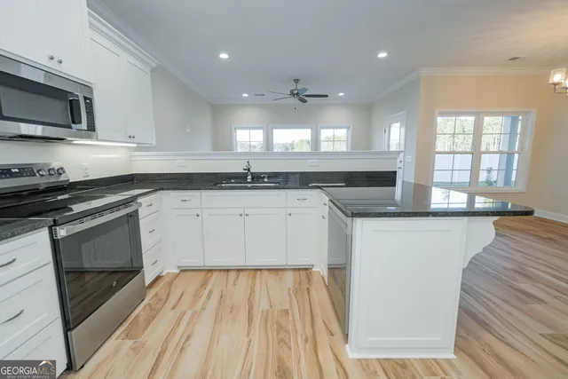 a kitchen with stainless steel appliances granite countertop a stove a sink and a microwave