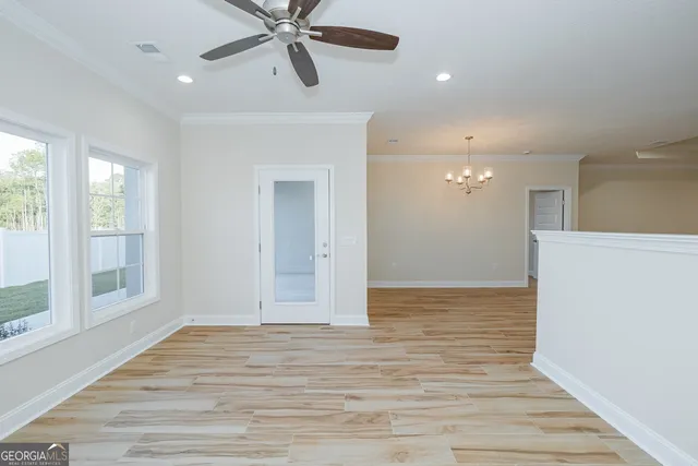 a view of empty room with wooden floor and fan