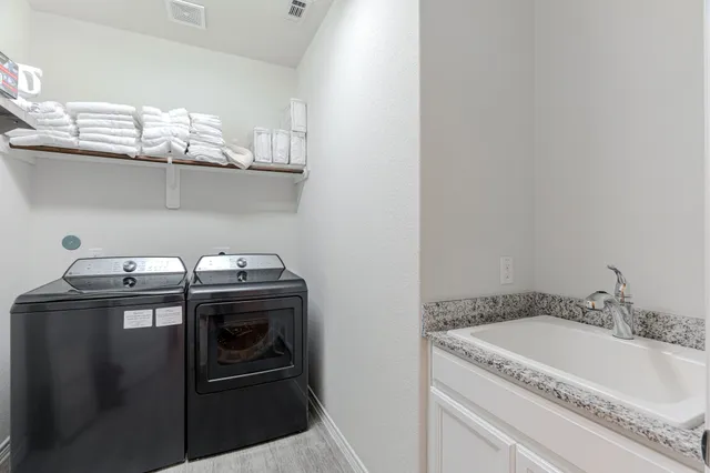 a bathroom with a granite countertop sink and washing machine