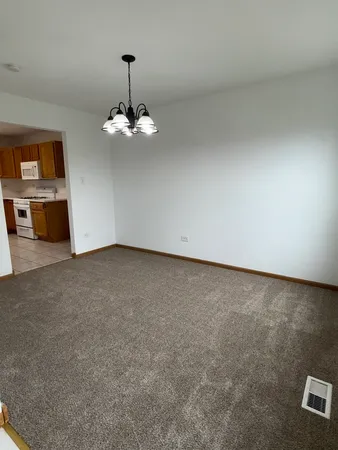an empty room with chandelier fan and windows