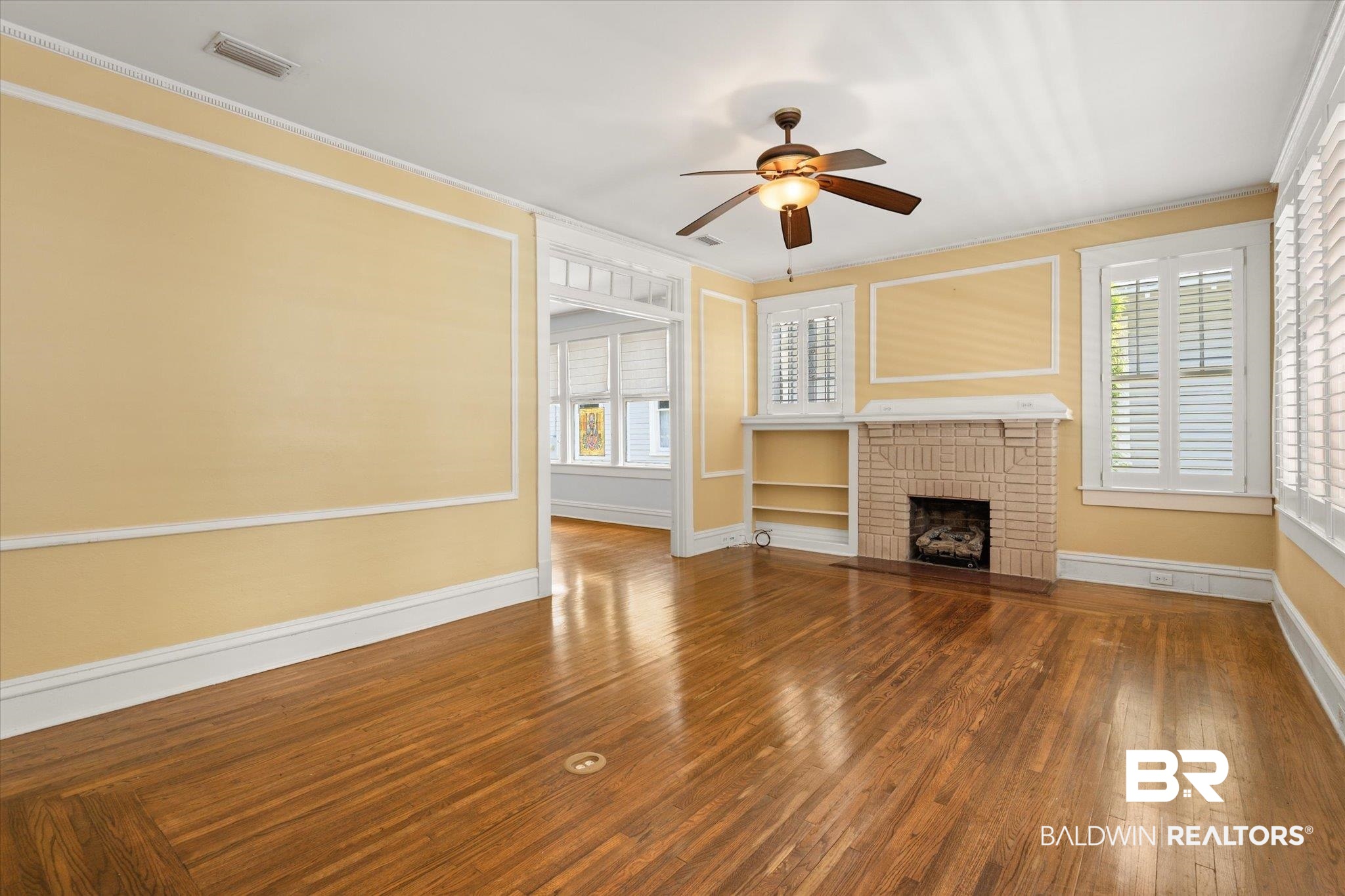 24 Macy Place Mobile, AL 36604 - Photo 5 of 38 Unfurnished living room featuring crown molding, ceiling fan, wood finished floors, a brick fireplace, and baseboards