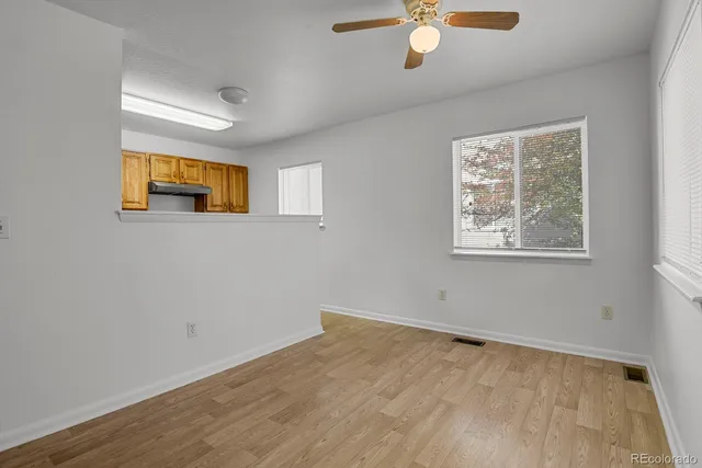 a view of an empty room with a window and wooden floor