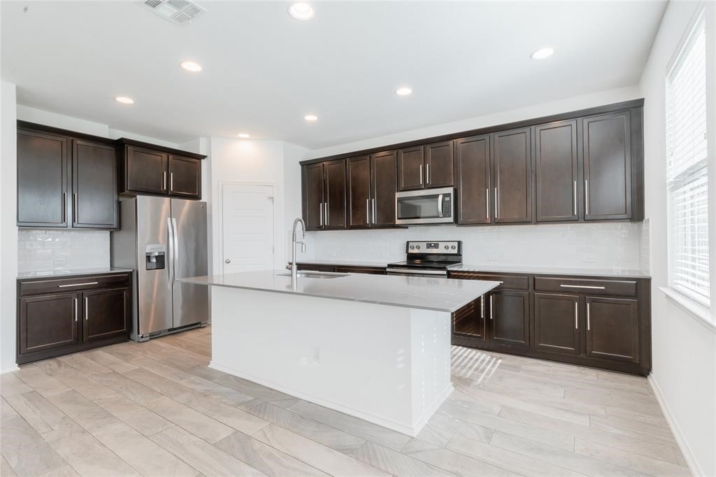 1333 Terrace View Drive Georgetown, TX 78628 - Photo 13 of 35 A contemporary kitchen showcasing dark wood cabinetry, stainless steel appliances, and an inviting island with a breakfast bar.