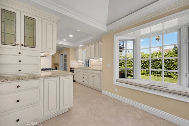 a kitchen with granite countertop white cabinets and white appliances with a large window