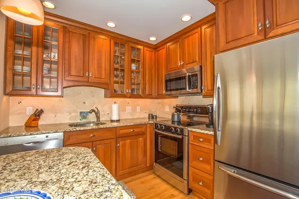 a kitchen with stainless steel appliances granite countertop a refrigerator and a stove top oven