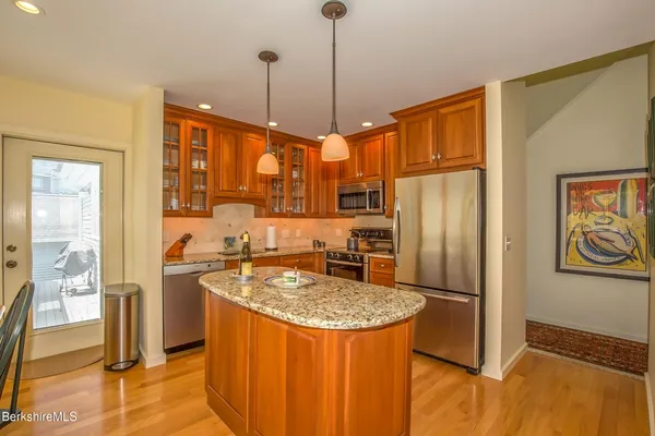 a kitchen with stainless steel appliances granite countertop a refrigerator a stove and a sink with wooden floor