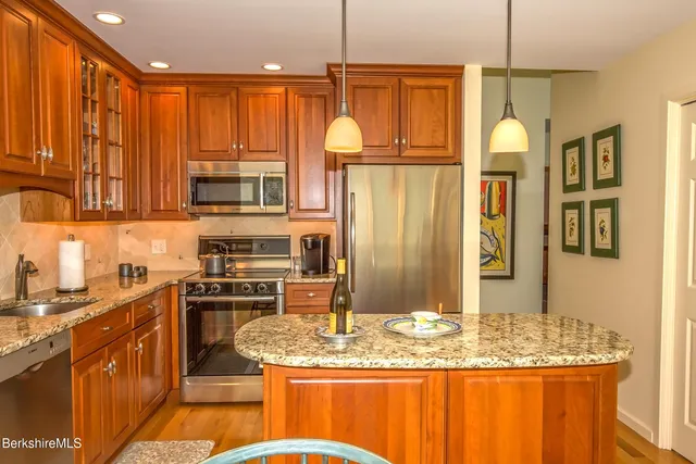 a kitchen with stainless steel appliances granite countertop a sink a stove and a wooden cabinets