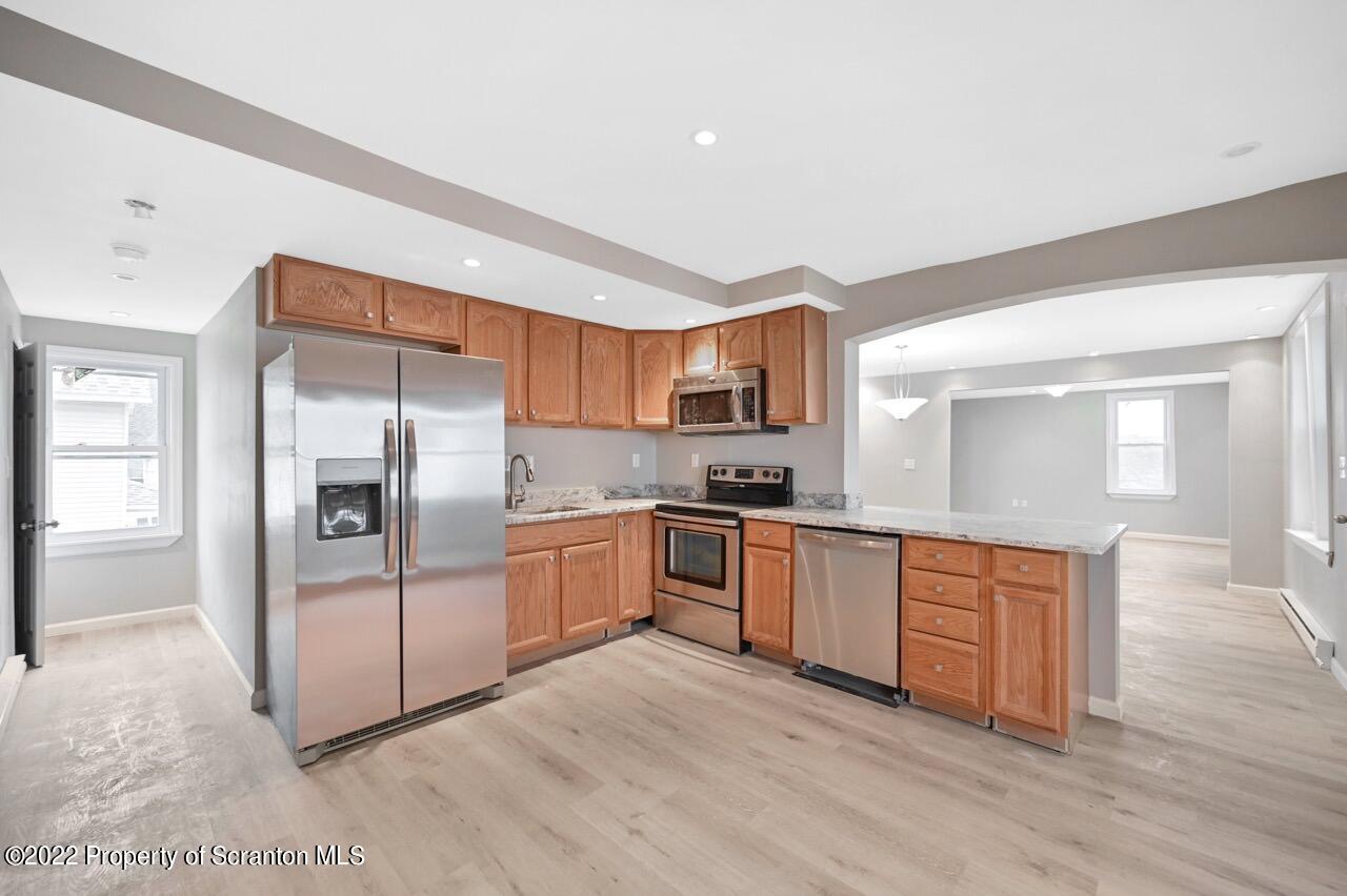 115 West High Street Taylor, PA 18517 - Photo 7 of 38 a open kitchen with stainless steel appliances granite countertop a refrigerator oven a sink dishwasher and white cabinets with wooden floor