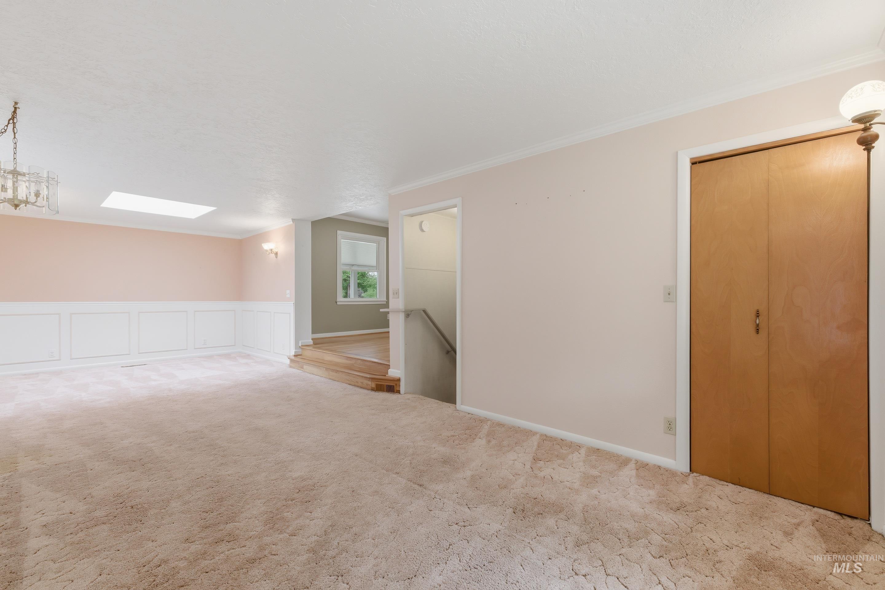 504 West Howe Street Boise, ID 83706 - Photo 12 of 47 Carpeted interior space featuring a partial wainscoting wall, a ceiling-mounted skylight, and a decorative chandelier