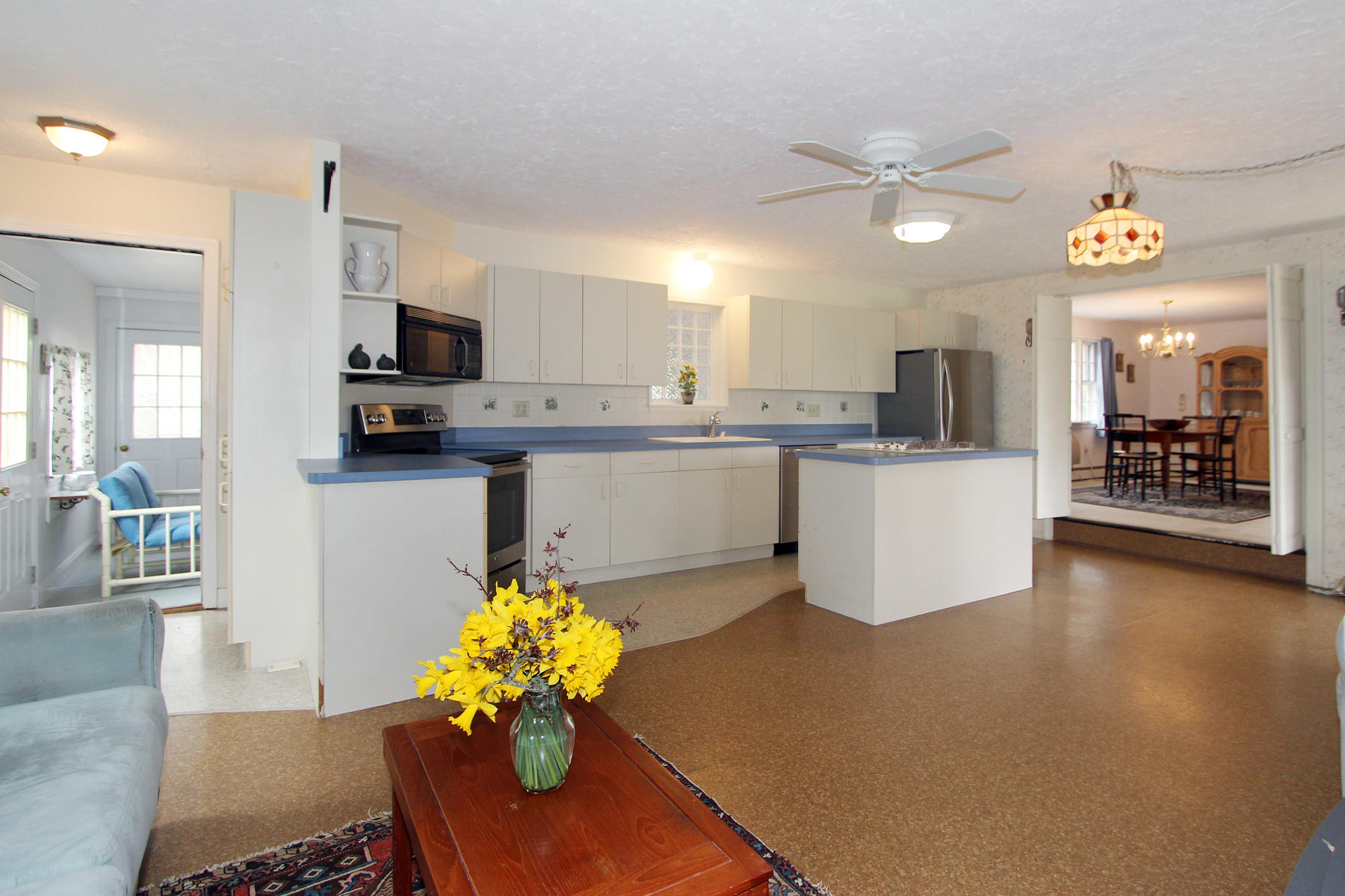 75 Lawton Road Eastham, MA 02642 - Photo 11 of 27 a kitchen with stainless steel appliances granite countertop a sink dishwasher a stove top oven a dining table and chairs with wooden floor