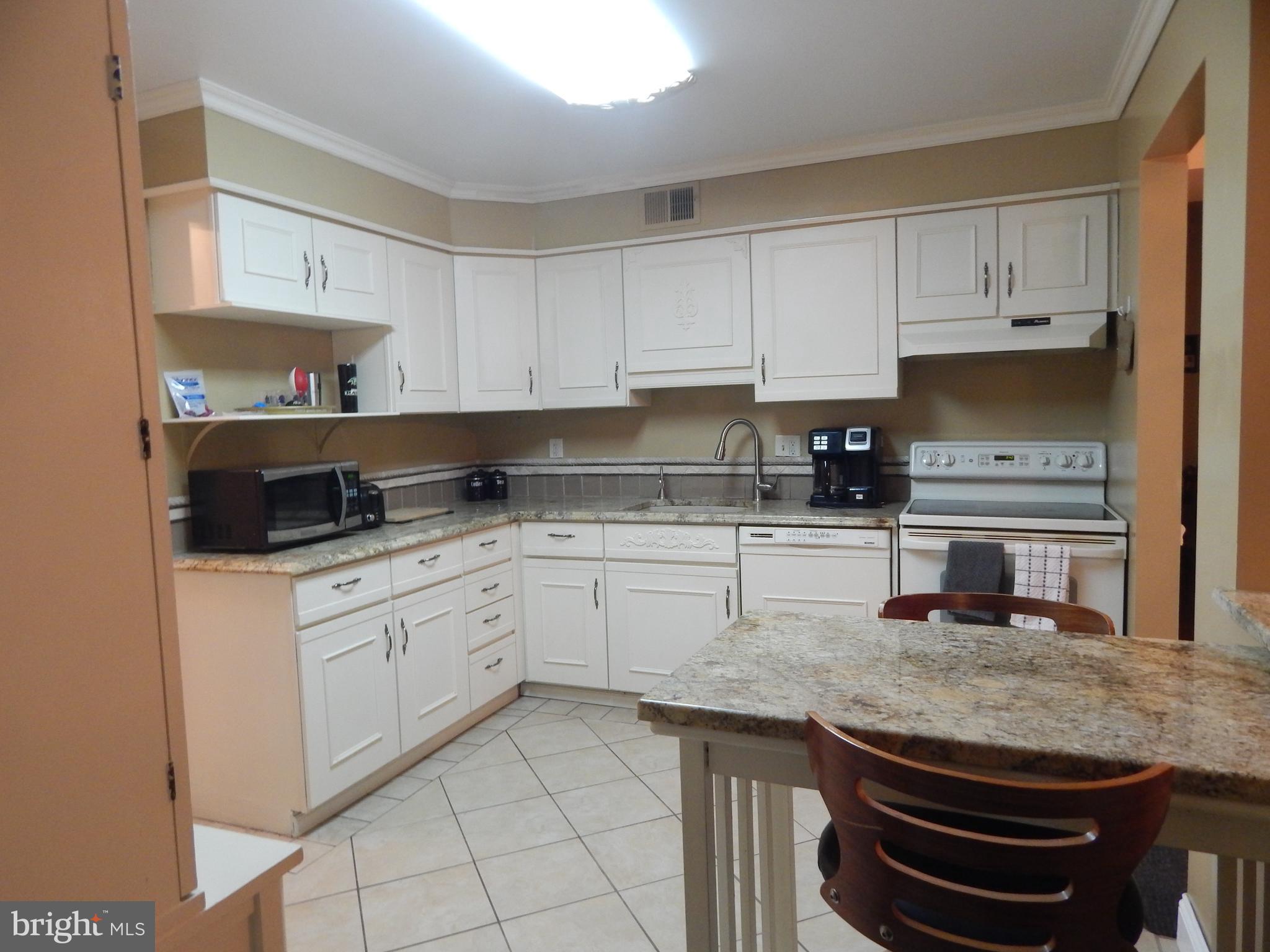 100 Castletown Road, Unit 101 Lutherville-Timonium, MD 21093 - Photo 4 of 18 a kitchen with granite countertop white cabinets and white appliances