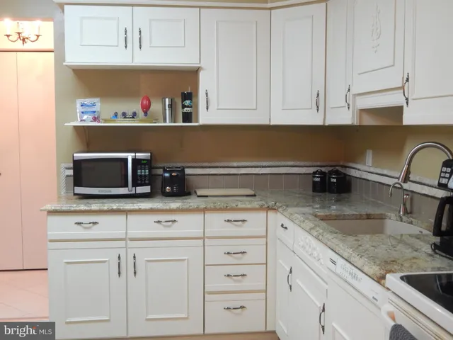a kitchen with white cabinets and sink