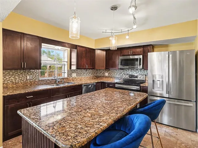 a kitchen with stainless steel appliances granite countertop wooden cabinets counter space and a center island