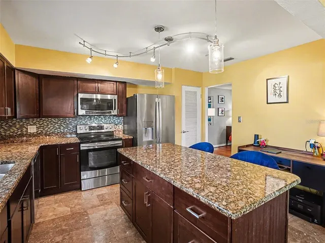 a kitchen with kitchen island granite countertop wooden cabinets and a refrigerator