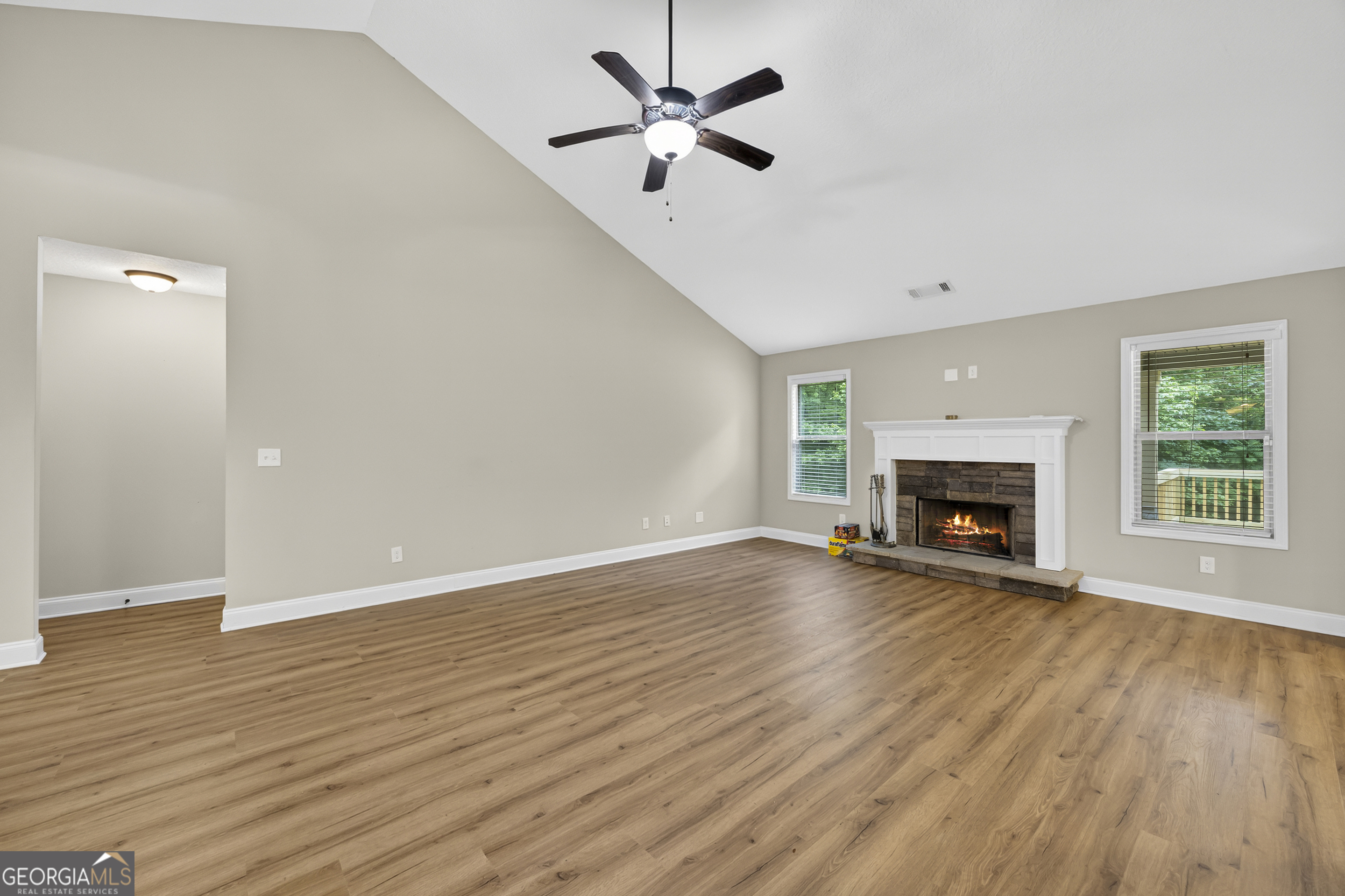 717 Oconee Lane Commerce, GA 30529 - Photo 14 of 57 an empty room with wooden floor a ceiling fan a fireplace and windows