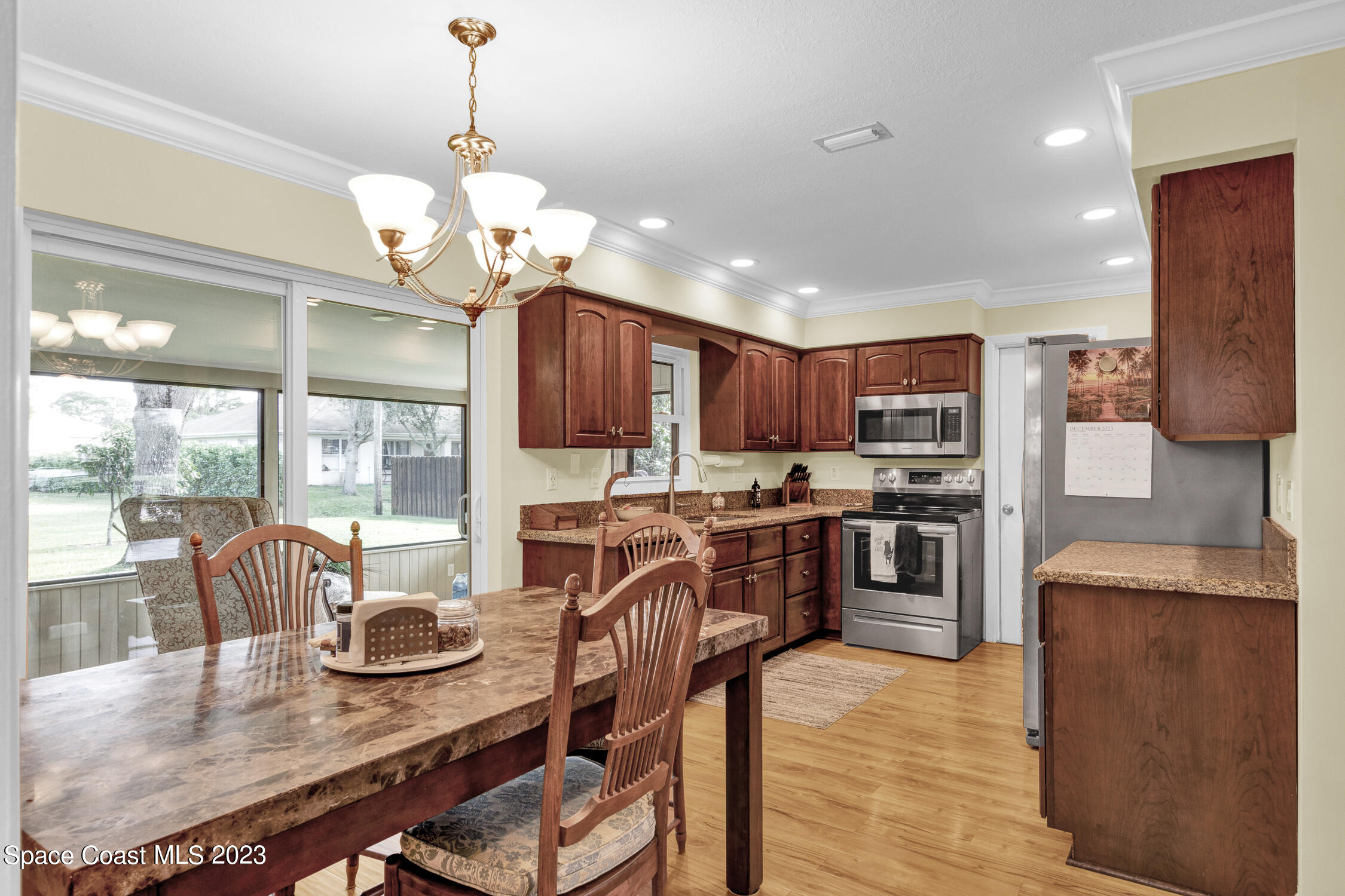 461 Easy Street Sebastian, FL 32958 - Photo 11 of 31 a kitchen with stainless steel appliances kitchen island granite countertop a stove top oven a refrigerator a kitchen island a dining table and chairs with wooden floor