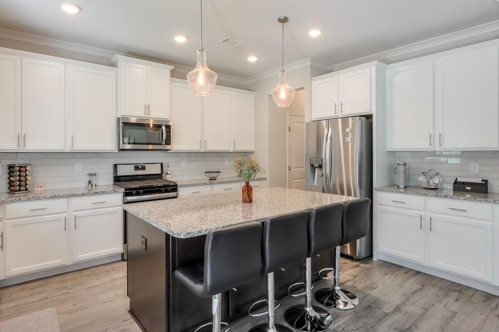 4688 Cantrell Road Flowery Branch, GA 30542 - Photo 14 of 39 a kitchen with stainless steel appliances granite countertop a table chairs sink refrigerator and microwave
