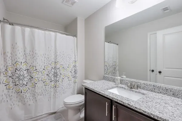 a bathroom with a granite countertop sink toilet and mirror